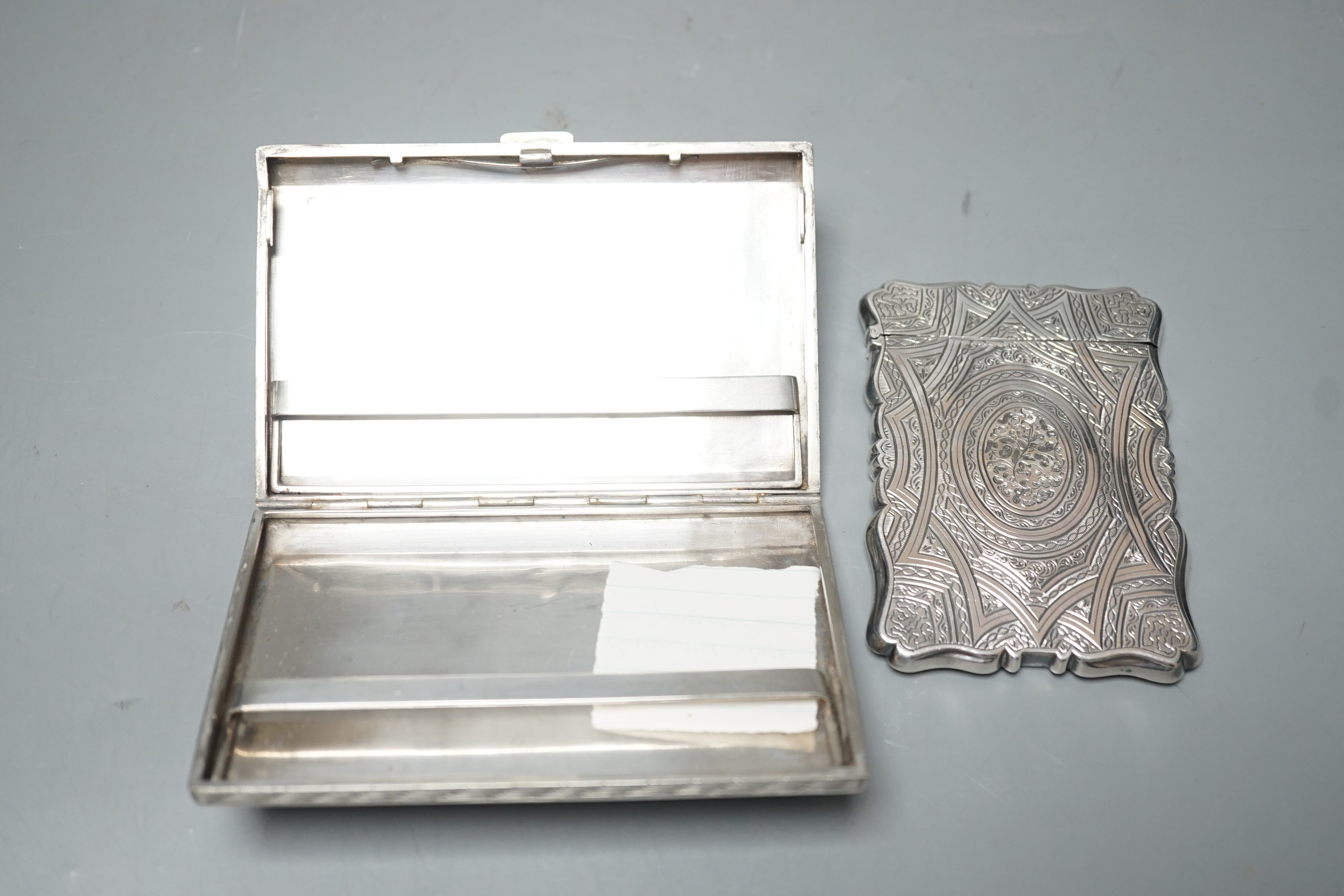 An engraved white metal card case, makers mark only AT, 97mm, together with an engraved 800 standard cigarette case, gross weight 8.9oz.